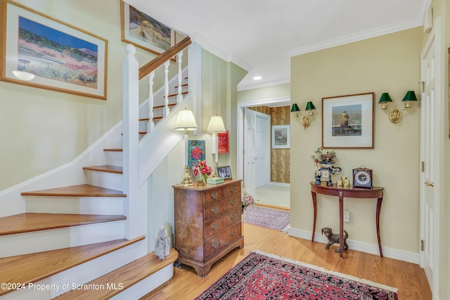 stairs with hardwood / wood-style floors and crown molding