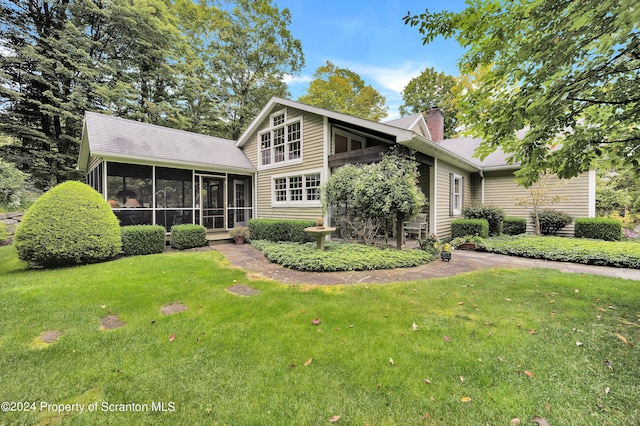 rear view of property with a lawn and a sunroom