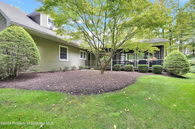 rear view of house featuring a yard and a sunroom