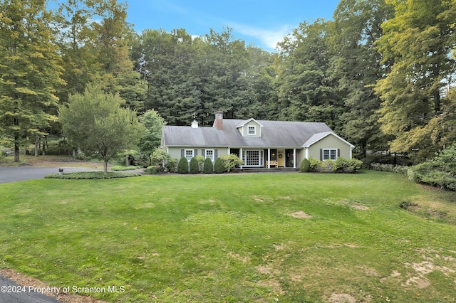 cape cod house featuring covered porch and a front lawn