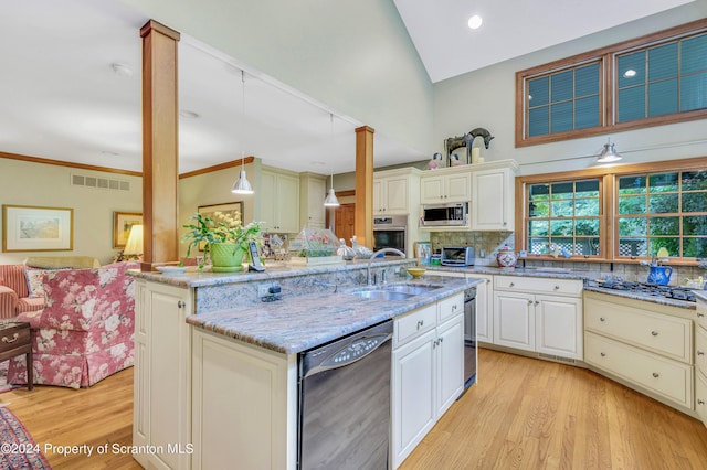 kitchen with tasteful backsplash, stainless steel appliances, sink, decorative light fixtures, and a center island with sink