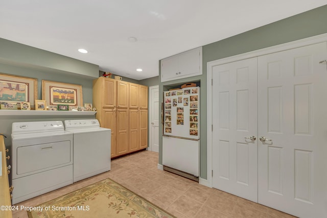 clothes washing area with cabinets, light tile patterned floors, and washer and clothes dryer