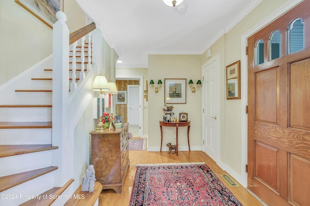 foyer entrance featuring light hardwood / wood-style floors and crown molding