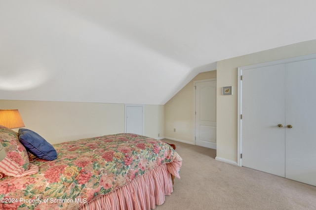 bedroom with a closet, light colored carpet, and vaulted ceiling