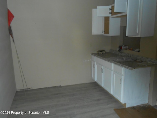 kitchen featuring light stone counters, white cabinetry, and light hardwood / wood-style flooring