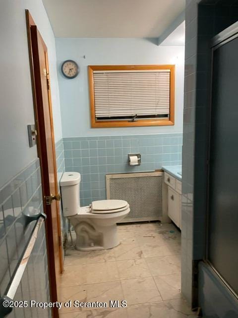 full bathroom with vanity, radiator heating unit, wainscoting, tile walls, and toilet