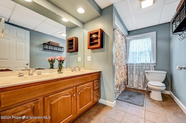 bathroom featuring vanity, a drop ceiling, tile patterned flooring, and toilet