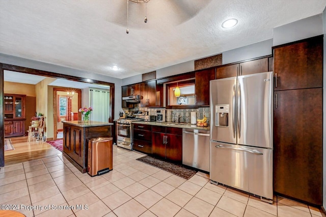 kitchen featuring a center island, sink, tasteful backsplash, ventilation hood, and appliances with stainless steel finishes