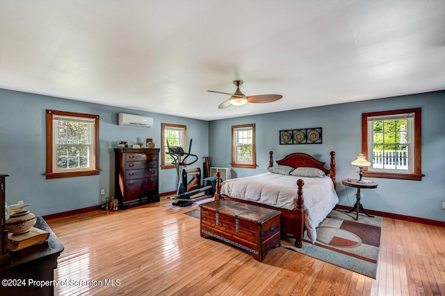 bedroom featuring ceiling fan, light hardwood / wood-style floors, and an AC wall unit