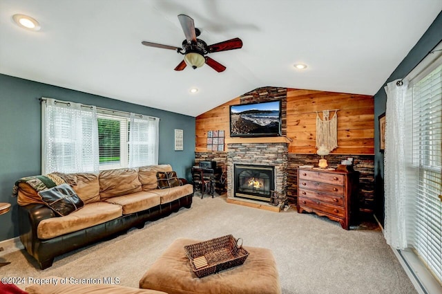 carpeted living room with a stone fireplace, wooden walls, ceiling fan, and lofted ceiling