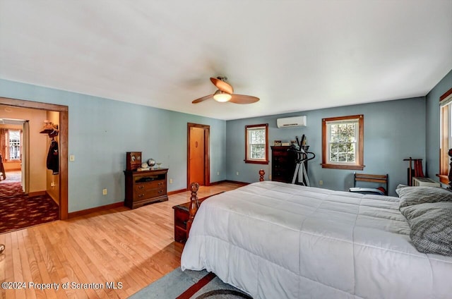 bedroom featuring ceiling fan, a spacious closet, light hardwood / wood-style flooring, a wall unit AC, and a closet