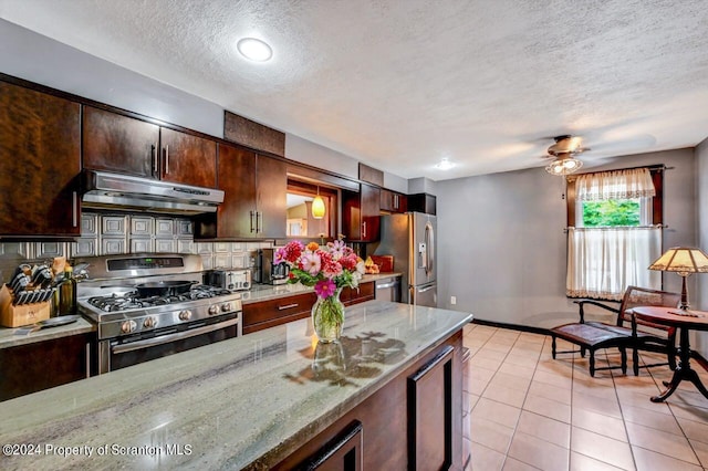 kitchen featuring ventilation hood, ceiling fan, light stone countertops, light tile patterned floors, and stainless steel appliances