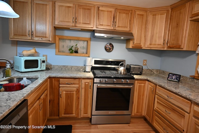 kitchen with dishwasher, stainless steel range with gas cooktop, sink, light wood-type flooring, and light stone counters