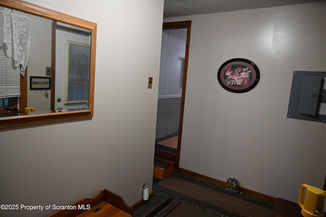 hallway featuring electric panel and a textured ceiling