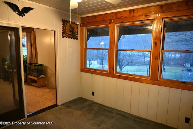 carpeted spare room with wooden walls