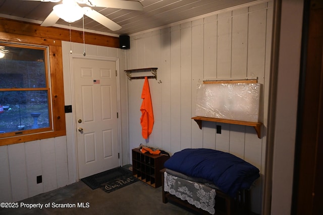 interior space featuring ceiling fan and wooden walls