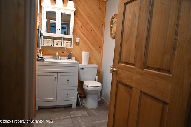 bathroom with tile patterned floors, vanity, toilet, and wooden walls