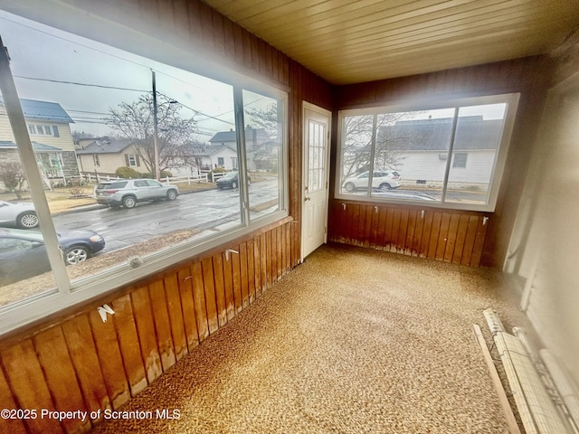 unfurnished sunroom with wooden ceiling and a residential view