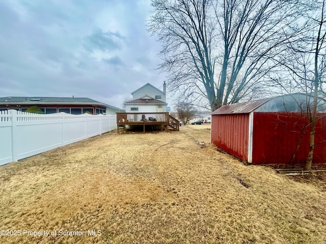 view of yard with fence, an outbuilding, and a wooden deck