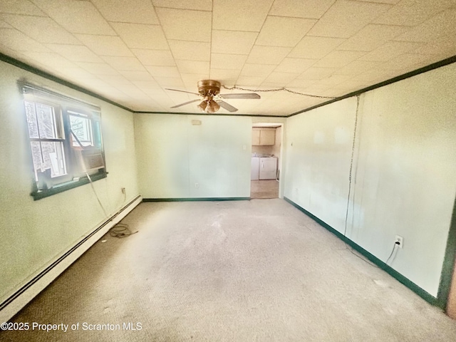 carpeted spare room featuring washing machine and dryer, ornamental molding, baseboard heating, and baseboards