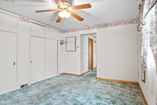 unfurnished bedroom featuring carpet, a closet, visible vents, baseboards, and ceiling fan