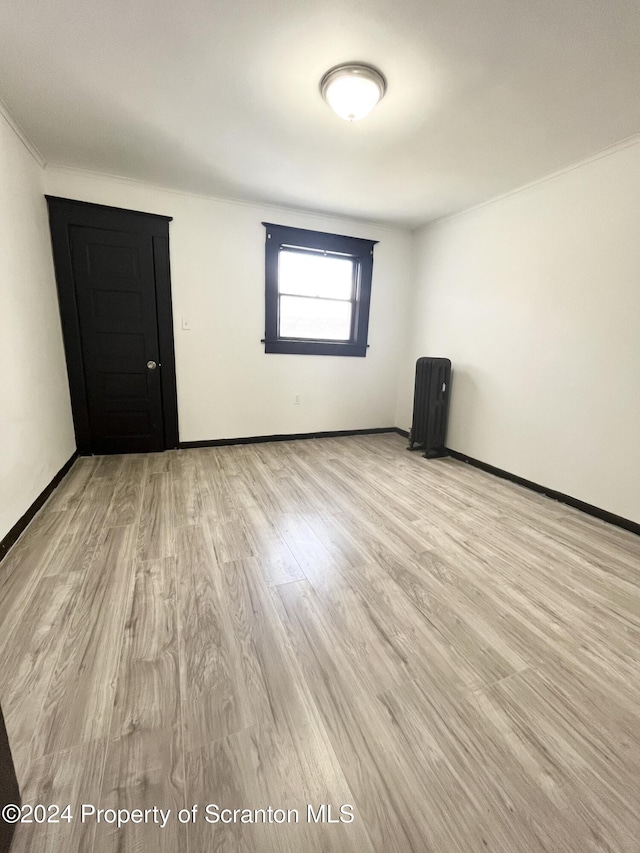 unfurnished room with light hardwood / wood-style flooring and radiator