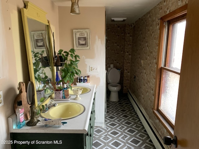 bathroom featuring a sink, a baseboard radiator, toilet, and double vanity