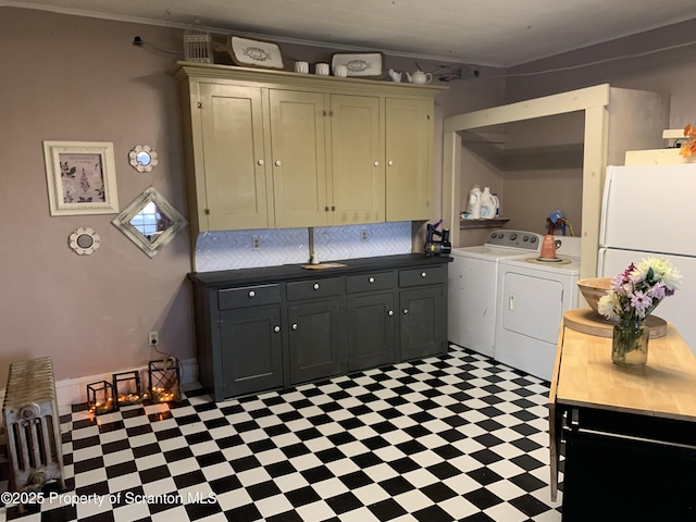 kitchen with independent washer and dryer, ornamental molding, backsplash, freestanding refrigerator, and light floors