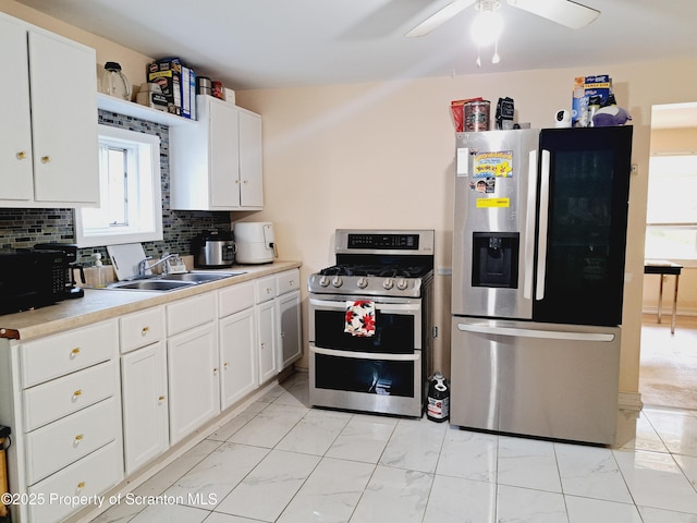 2127 Price St, Scranton, PA 18504 - kitchen with appliances with stainless steel finishes, light marble finish floors, ceiling fan, white cabinetry, and backsplash