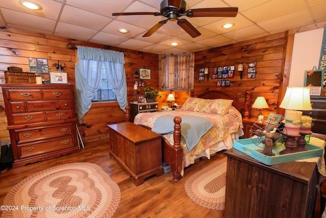 bedroom with ceiling fan, light hardwood / wood-style flooring, and a drop ceiling