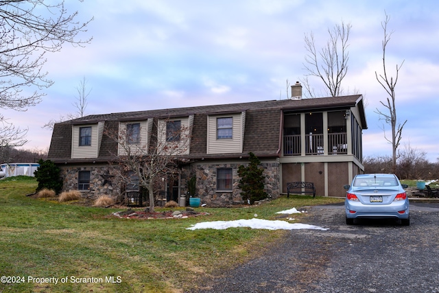 view of front of home with a sunroom and a yard