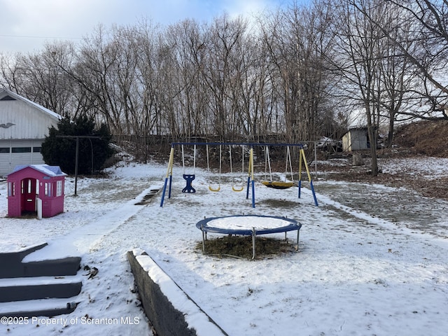 snowy yard with a playground and a trampoline