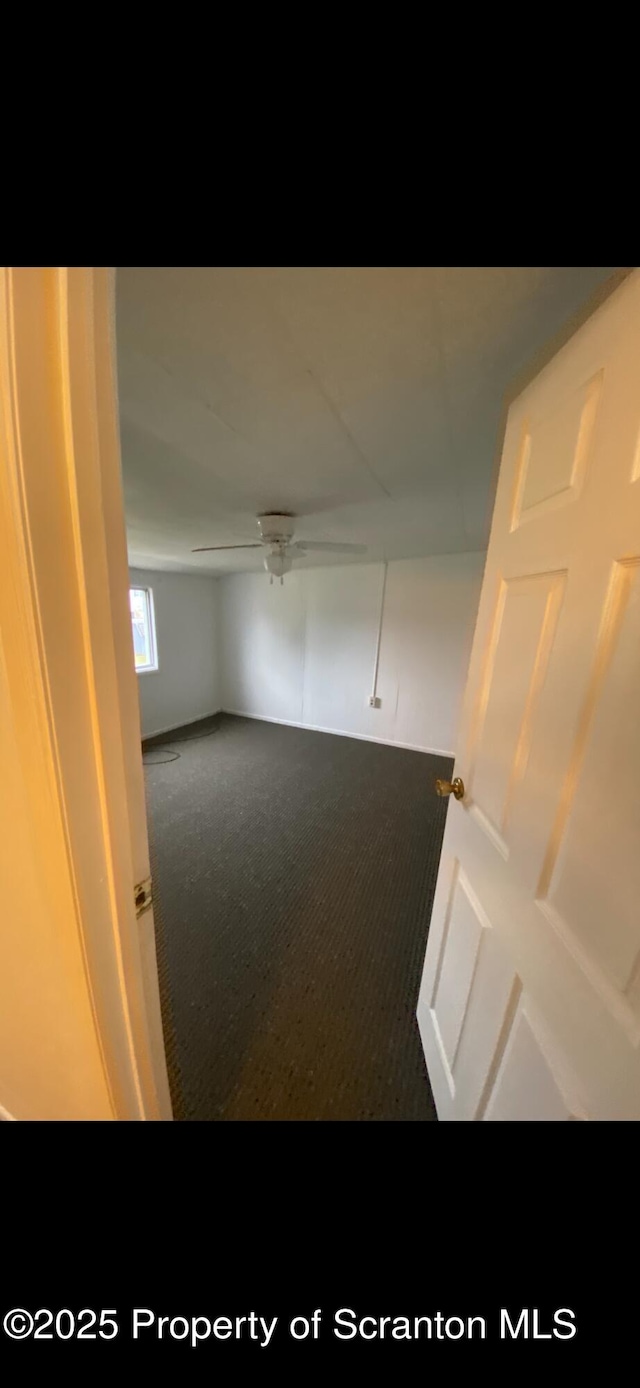 carpeted spare room featuring ceiling fan