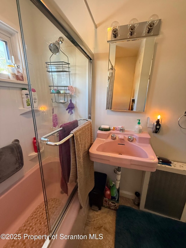 bathroom featuring a sink, a shower with shower door, and radiator heating unit