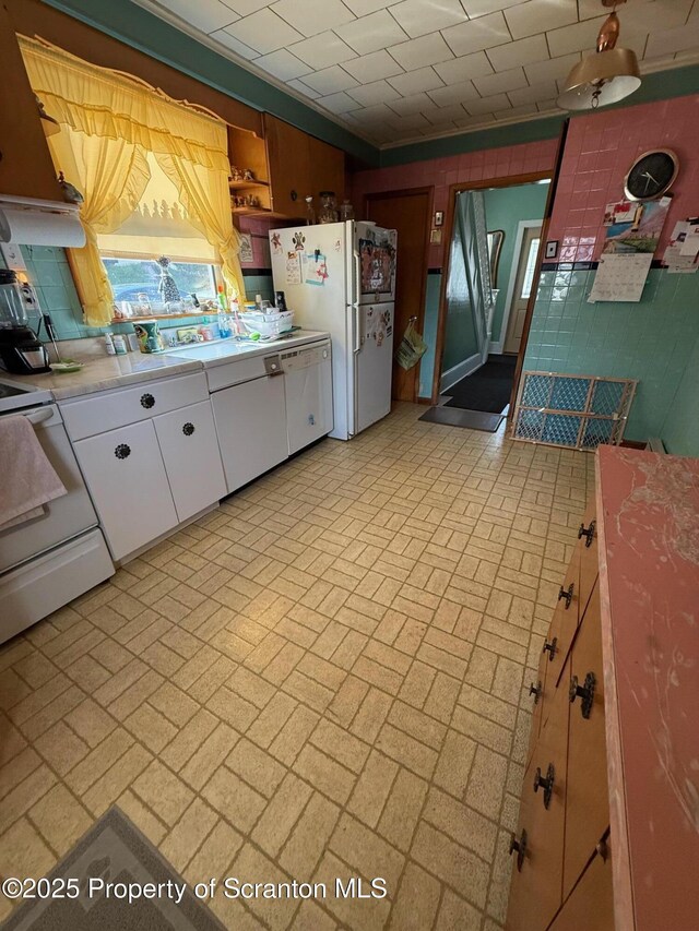 kitchen featuring white cabinets, light countertops, range, brick patterned floor, and freestanding refrigerator