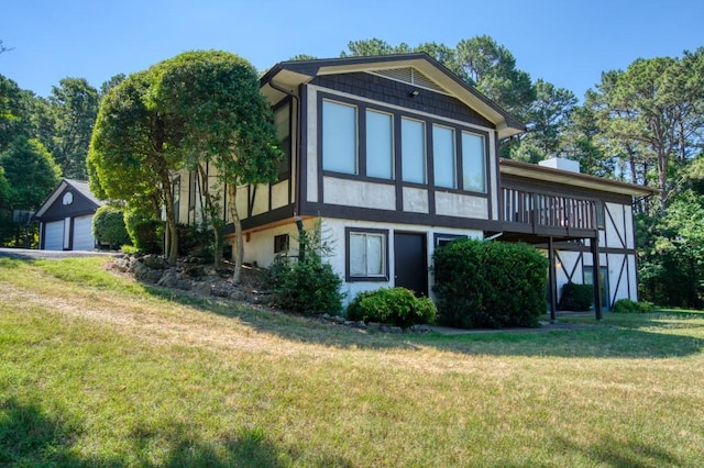 back of property featuring a wooden deck, a yard, and a garage