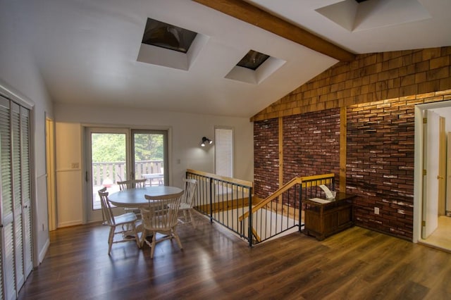 dining room with vaulted ceiling with skylight, brick wall, and dark hardwood / wood-style floors