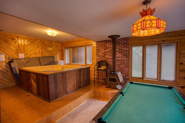 rec room featuring brick wall, pool table, wooden walls, and a wood stove