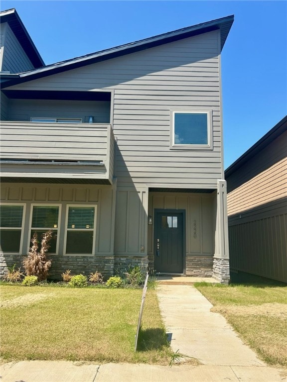 view of front of home with a balcony and a front lawn