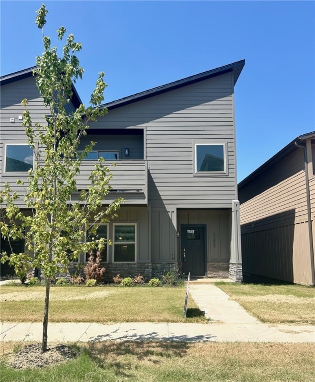 view of front of home featuring a front yard and a balcony