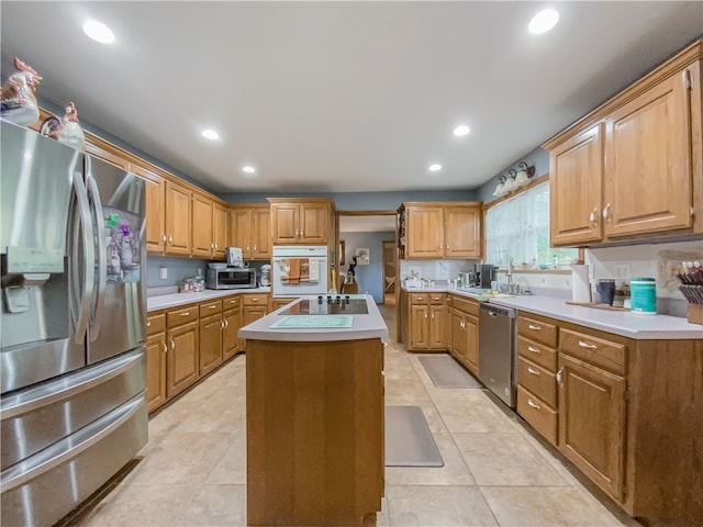 kitchen with an island with sink, light tile flooring, appliances with stainless steel finishes, and sink