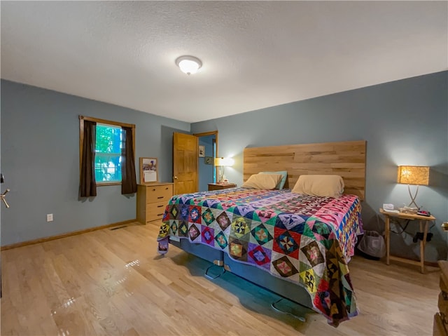 bedroom with light hardwood / wood-style floors and a textured ceiling