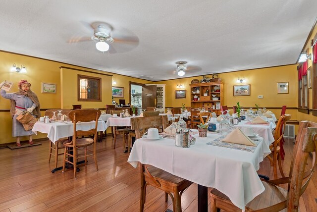 dining space with ceiling fan, light wood-type flooring, and a textured ceiling