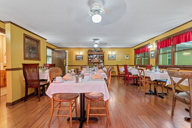 dining room with wood-type flooring, ceiling fan, and ornamental molding