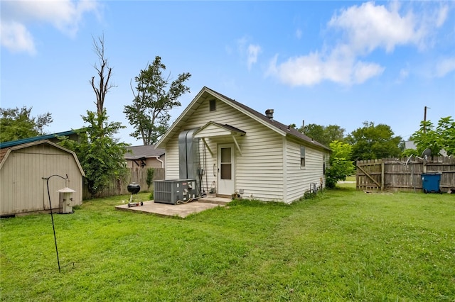 rear view of property featuring a yard, a shed, and a patio