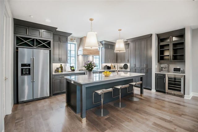 kitchen featuring wine cooler, hanging light fixtures, light wood-type flooring, and stainless steel appliances