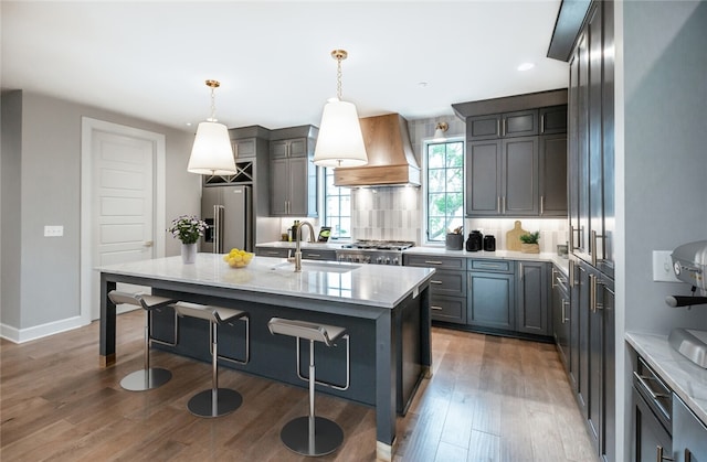 kitchen featuring pendant lighting, sink, custom range hood, stainless steel appliances, and tasteful backsplash