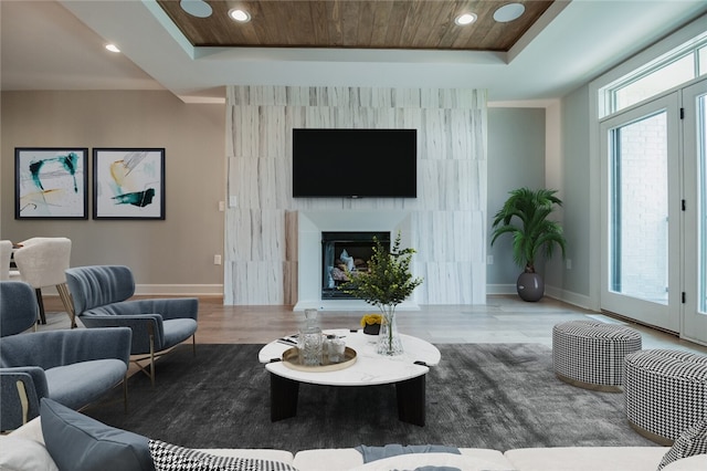 living room with a raised ceiling, hardwood / wood-style floors, and wood ceiling