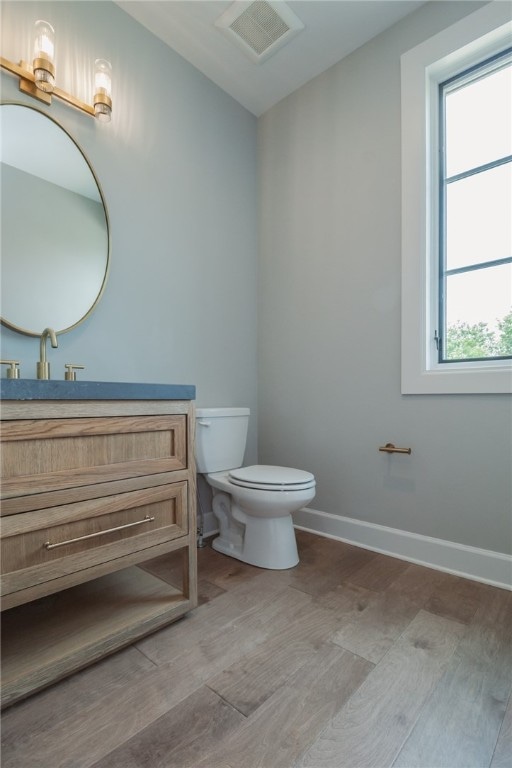 bathroom featuring toilet, hardwood / wood-style floors, plenty of natural light, and vanity