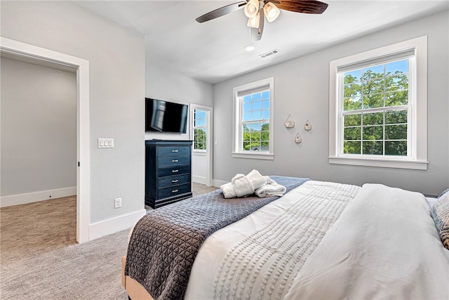 carpeted bedroom with ceiling fan and multiple windows